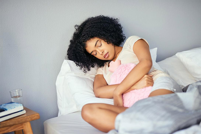 woman-with-a-hot-water-botle-on-her-stomach-which-is-a-home-remedy-for-menstrual-cramps
